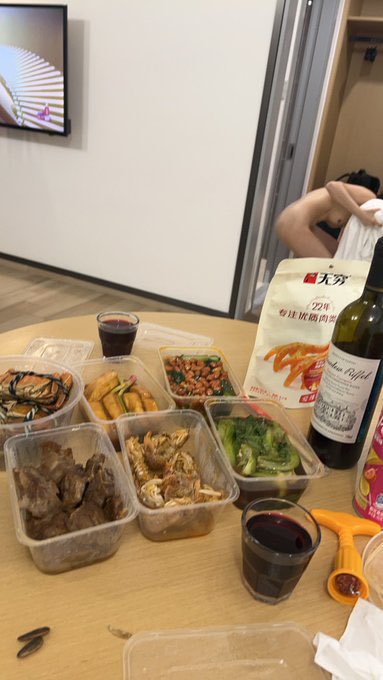 一个男人站在一张桌子前,一瓶葡萄酒和一杯红酒。