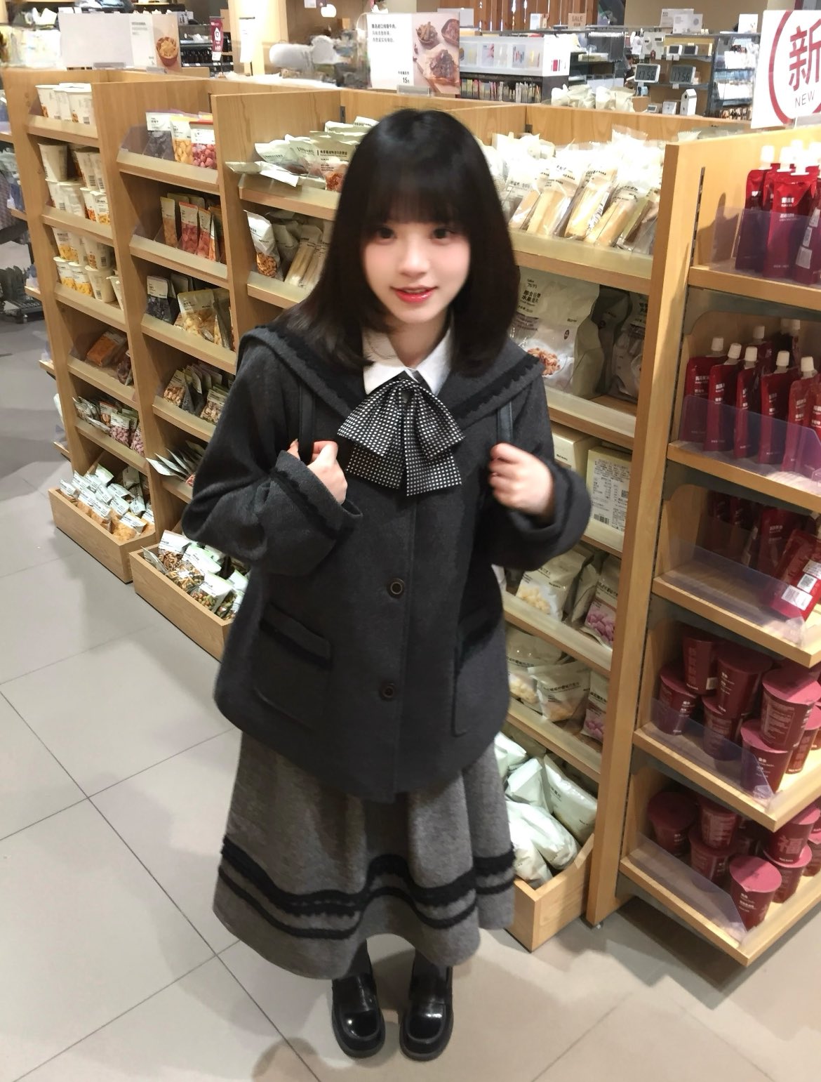 一个穿着灰色外套和黑色裙子的女孩为相机姿势。