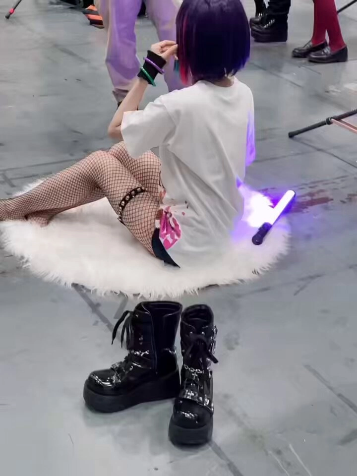 一位穿着鱼网袜的女孩坐在白皮毛毯上。