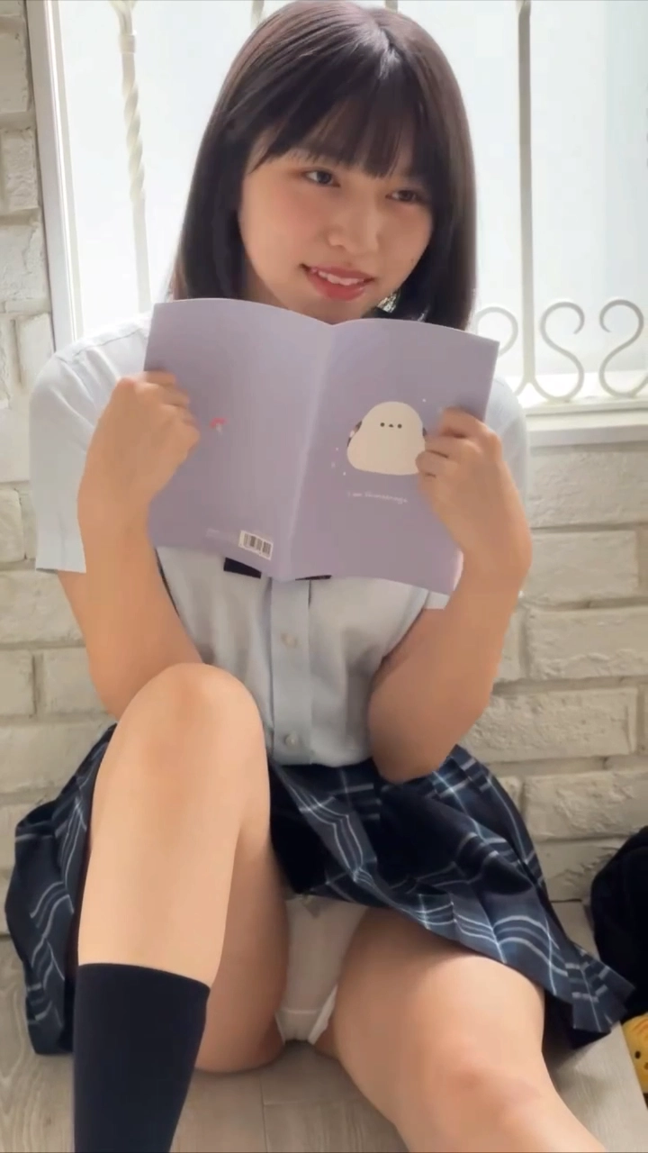 一个女人正在读一本书,她穿着裙子。