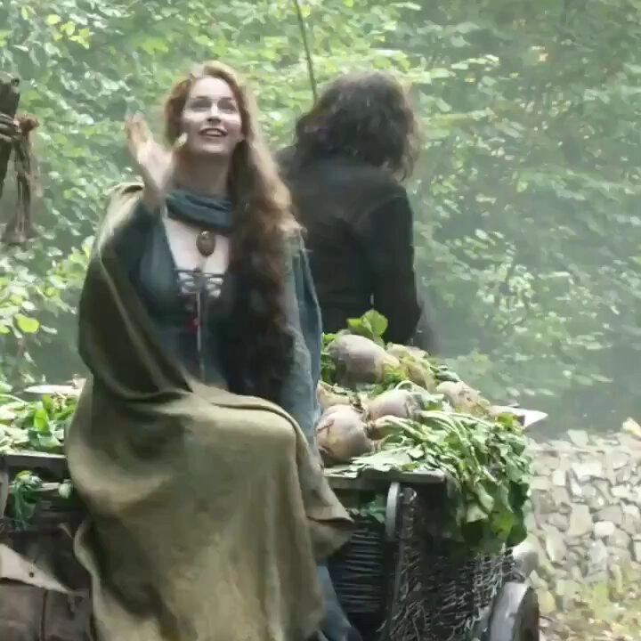 一位穿着绿色衣服的女人坐在一辆装满蔬菜的马车上。