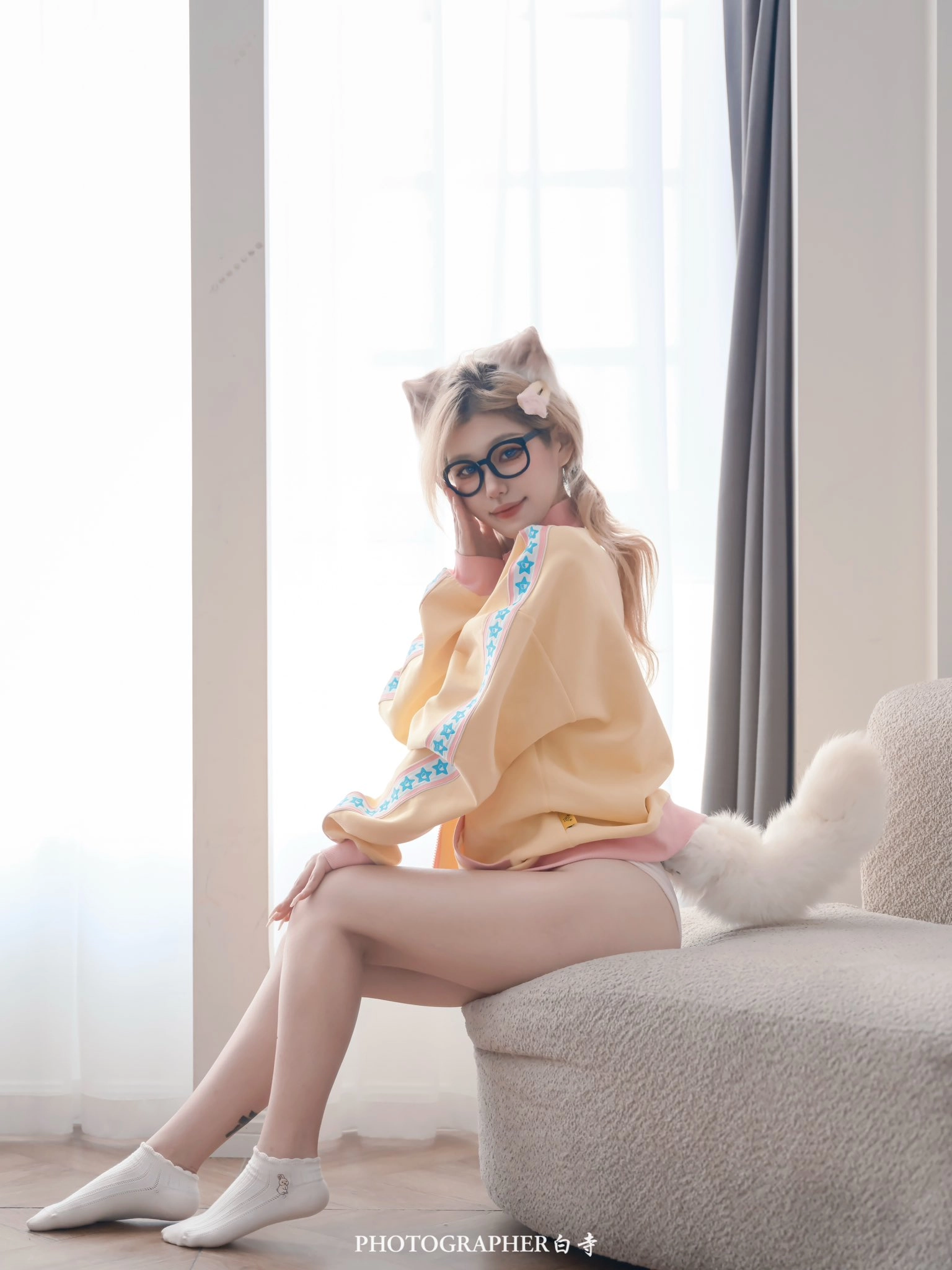 一位戴眼镜的女人,一只猫的尾巴坐在沙发上。