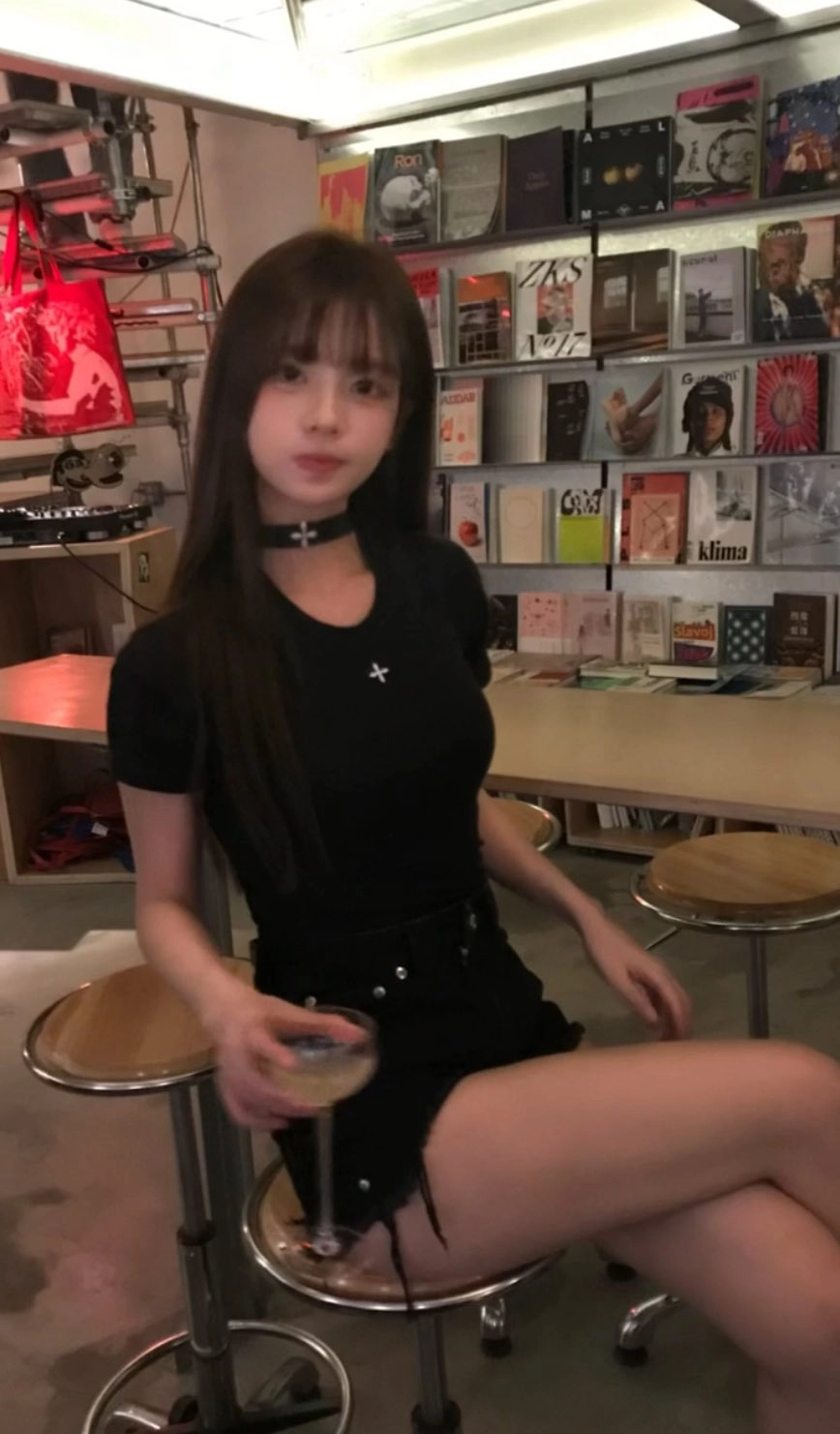 一位穿着黑色衬衫和黑色短裤的女人坐在椅子上。