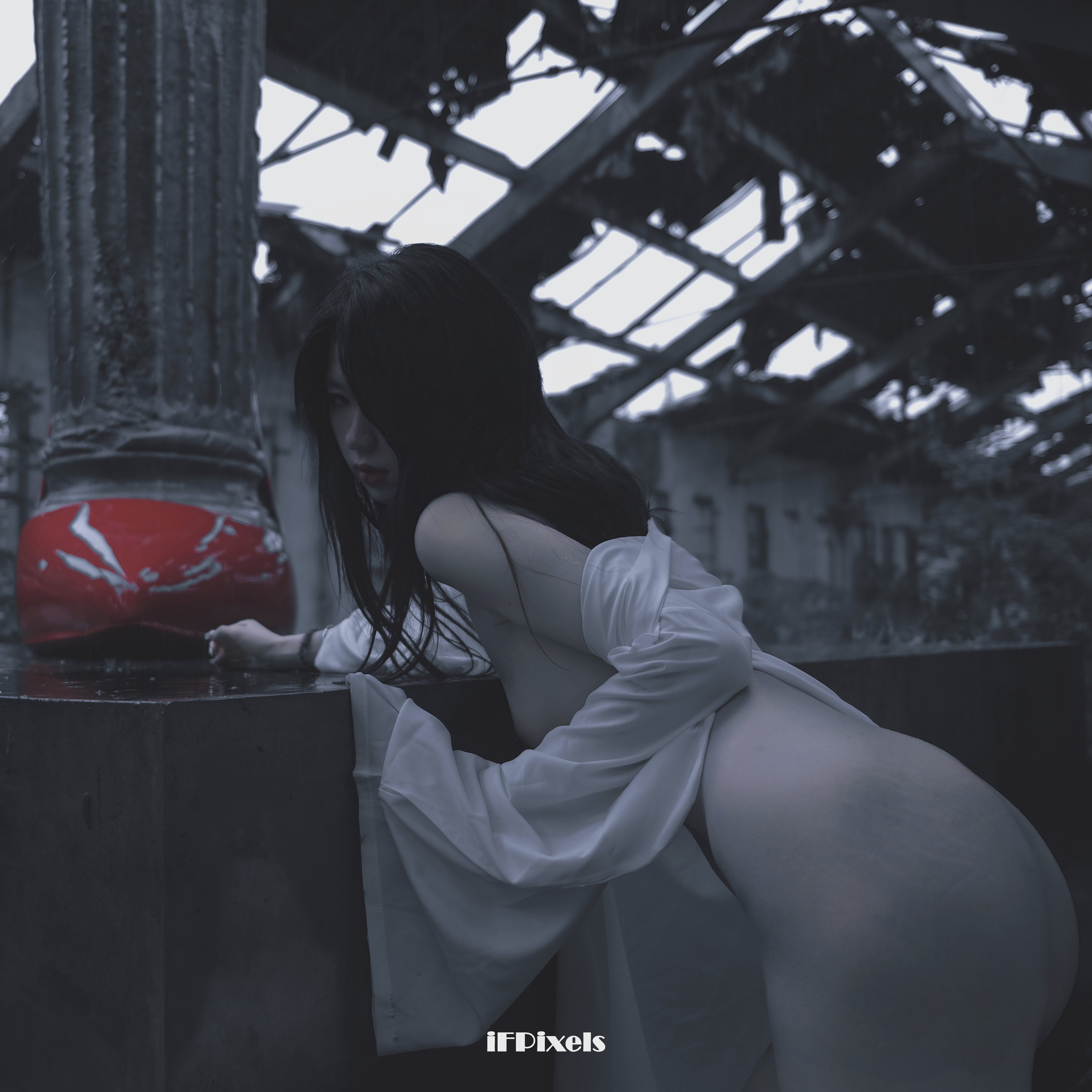 长头发和白色裙子的女人站在一个红色物体旁边。