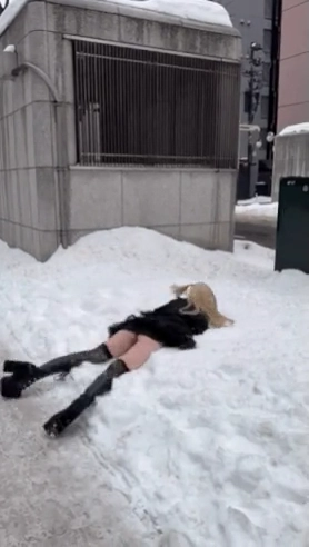 穿着黑色衣服的女人躺在雪地里。