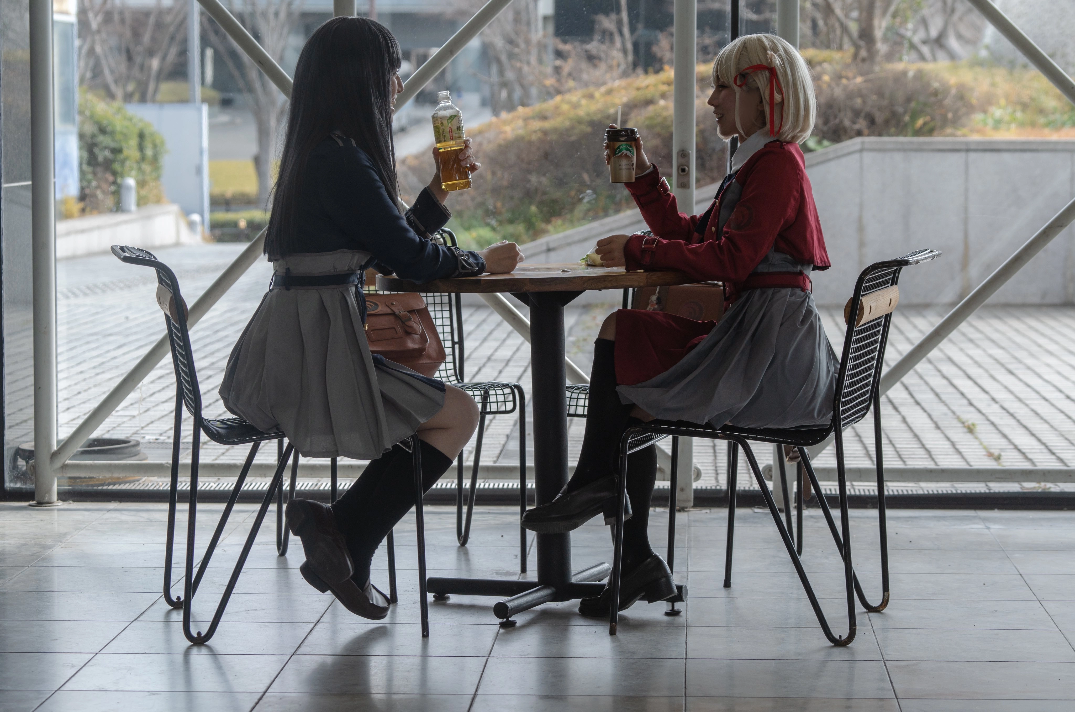 两个女孩坐在一张桌子上,享受饮料和对话。