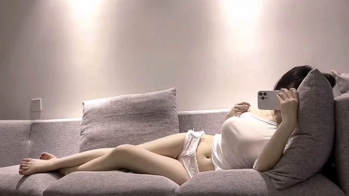 女人躺在沙发上拍个自拍。