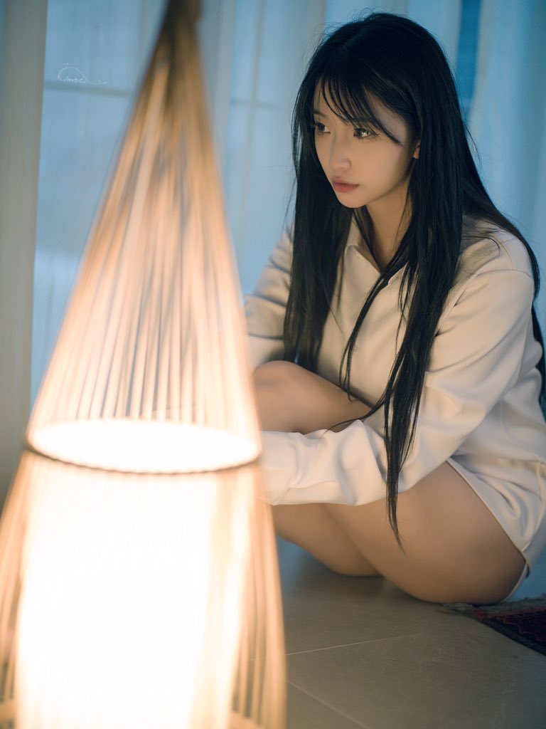 女人坐在地板上,站在一盏灯前。