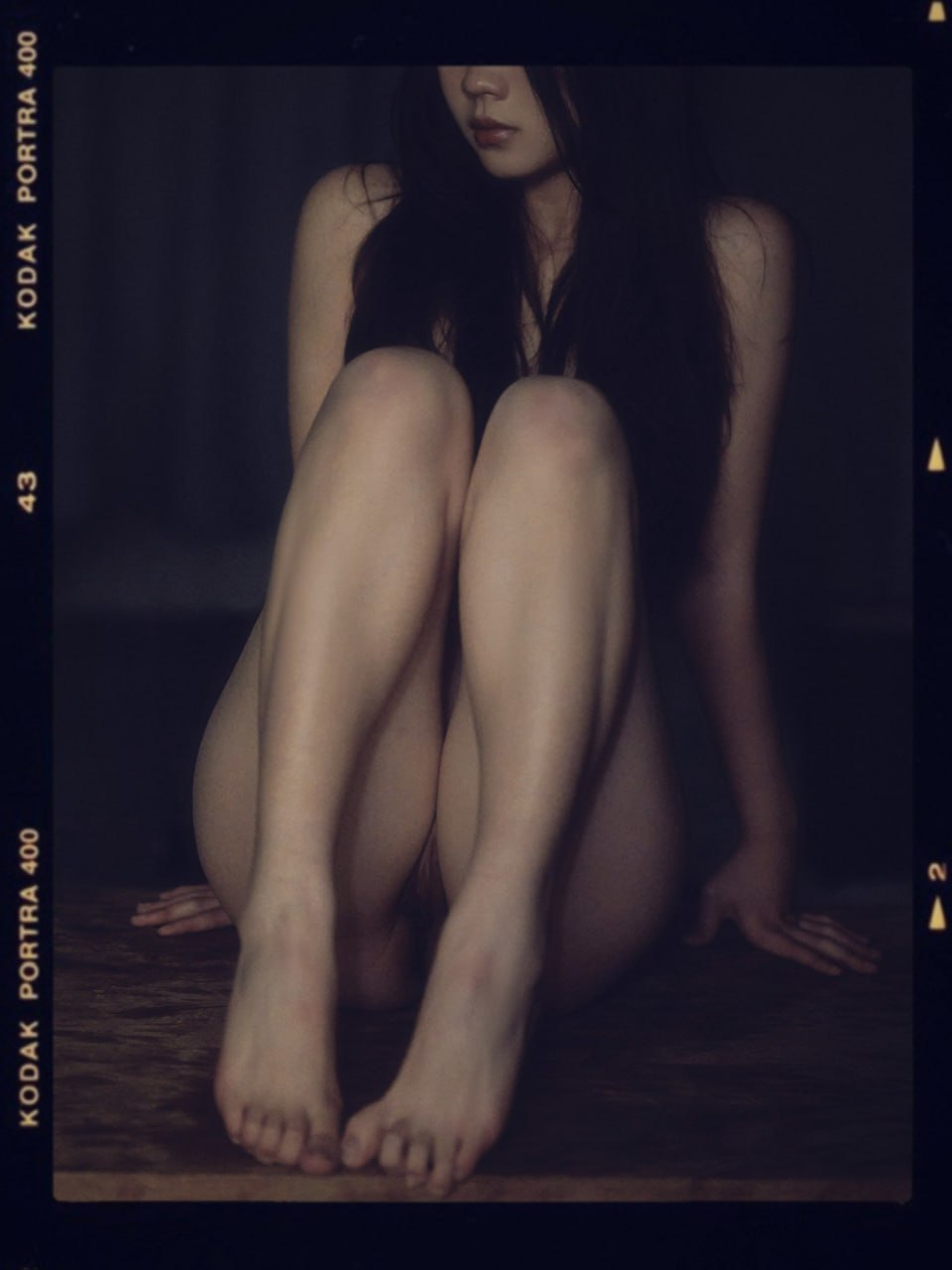 裸体的女人坐在木制的桌子上。