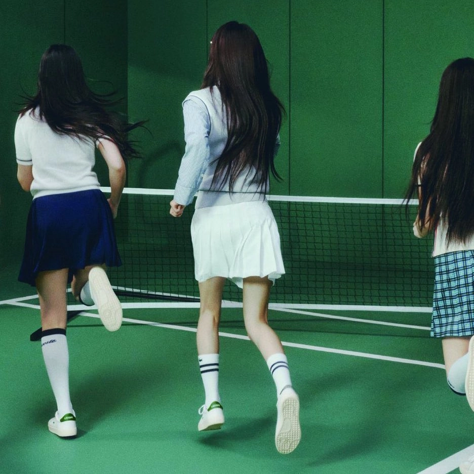 三个女孩在网球场上奔跑。