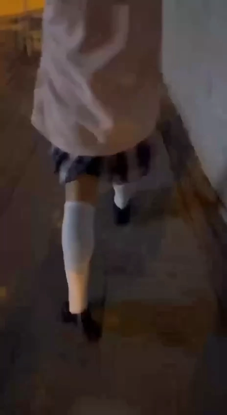 穿着粉红色夹克和白色袜子的女孩走在走廊上。