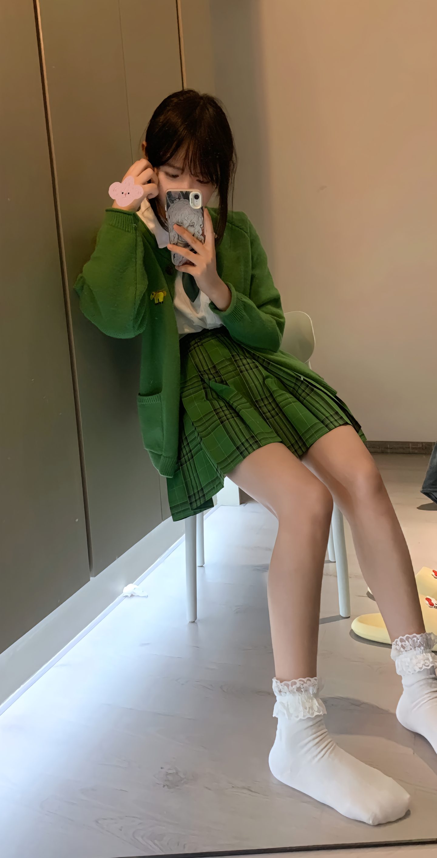 一位穿着一件绿色夹克和一件白色的裙子的女人正在拍自拍。