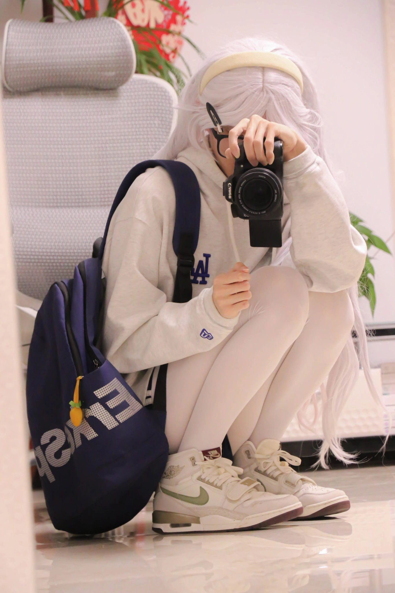 一位穿着蓝背包和白裤子的女孩正在拍照她的鞋子。