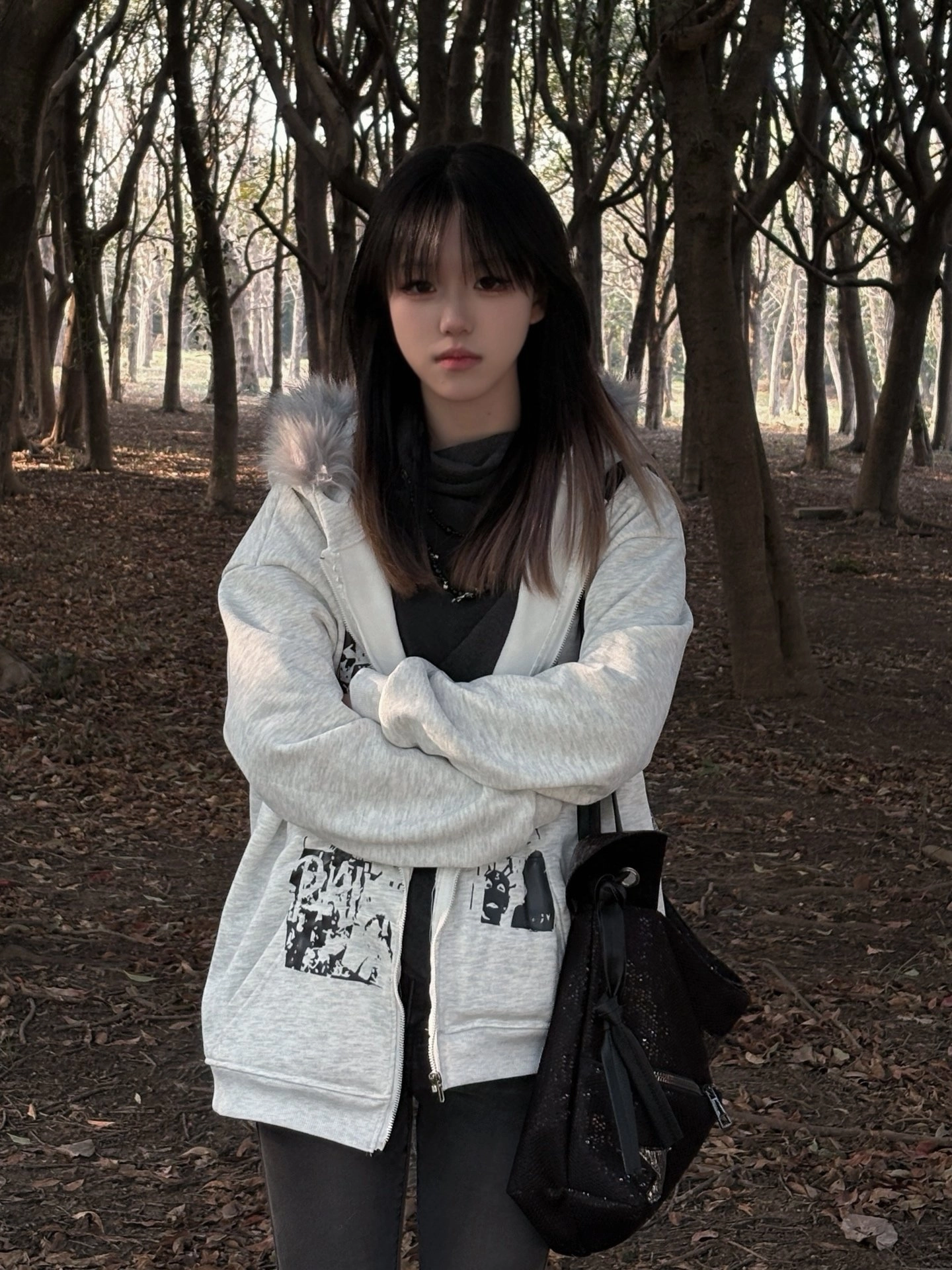 穿着白色夹克和黑色裤子的女人站在森林里。