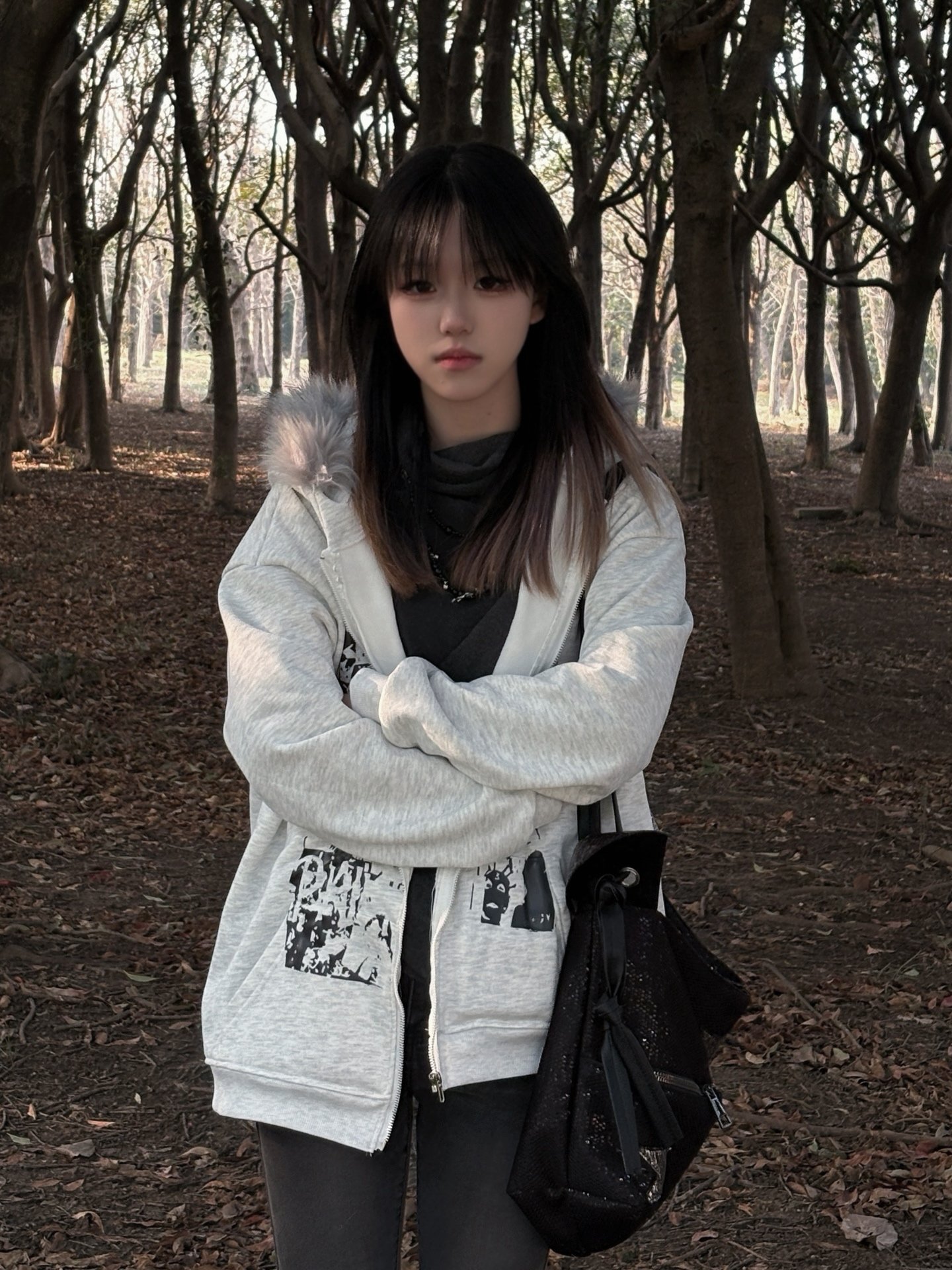 穿着白色夹克和黑色裤子的女人站在森林里。