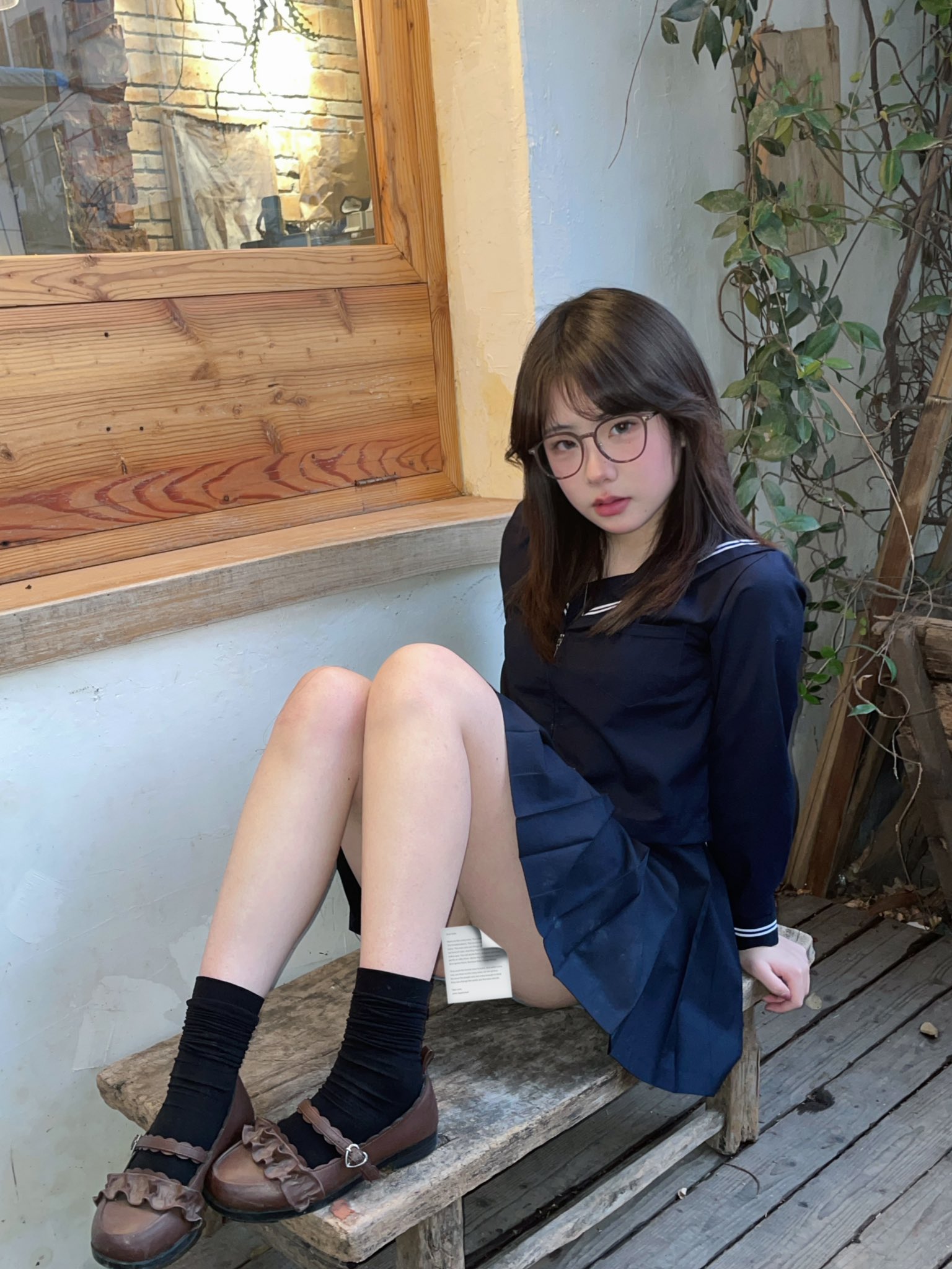 戴着眼镜和蓝色裙子的女人坐在一个凳子上。