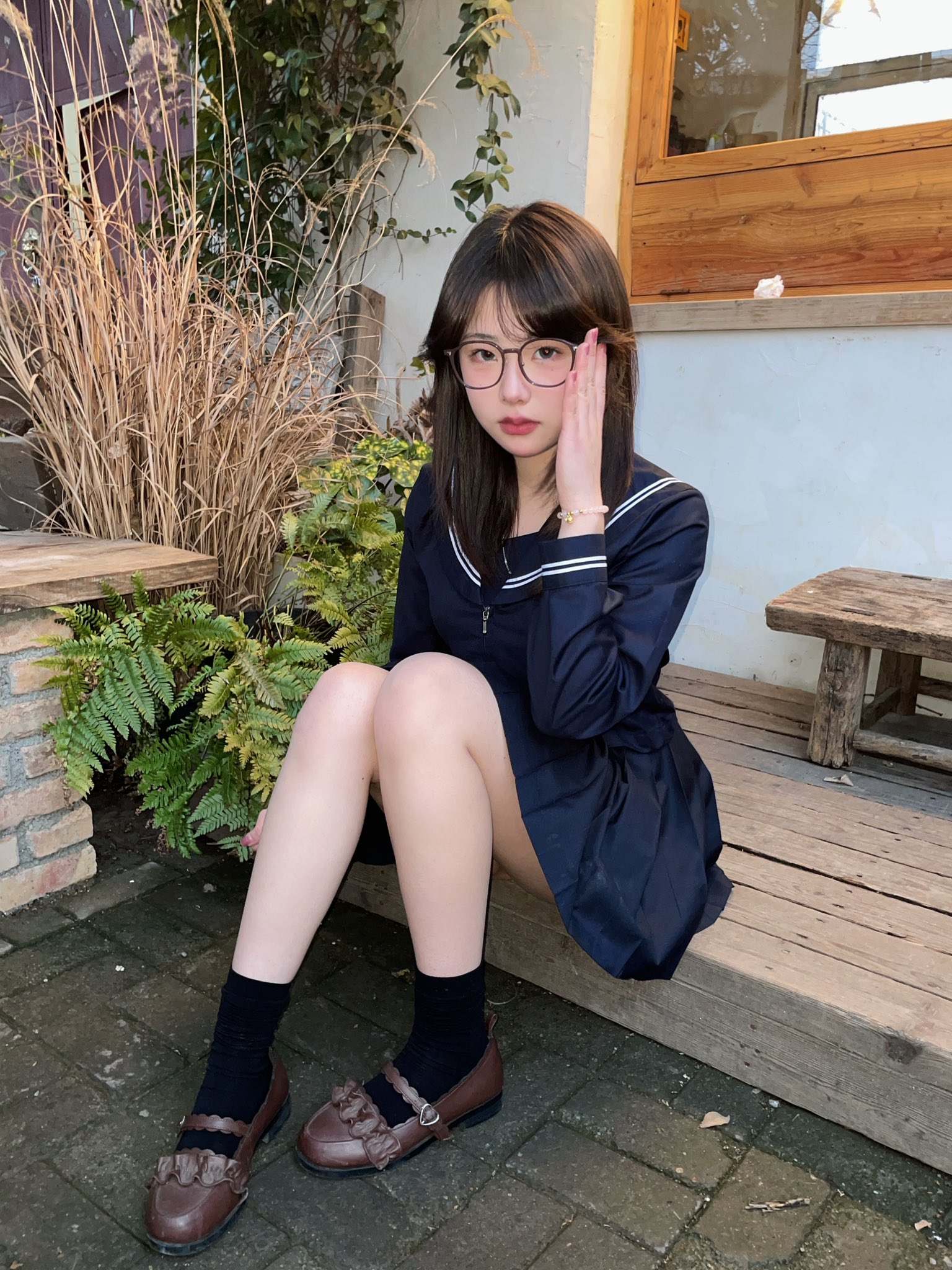 戴着眼镜和蓝色裙子的女人坐在一个凳子上。