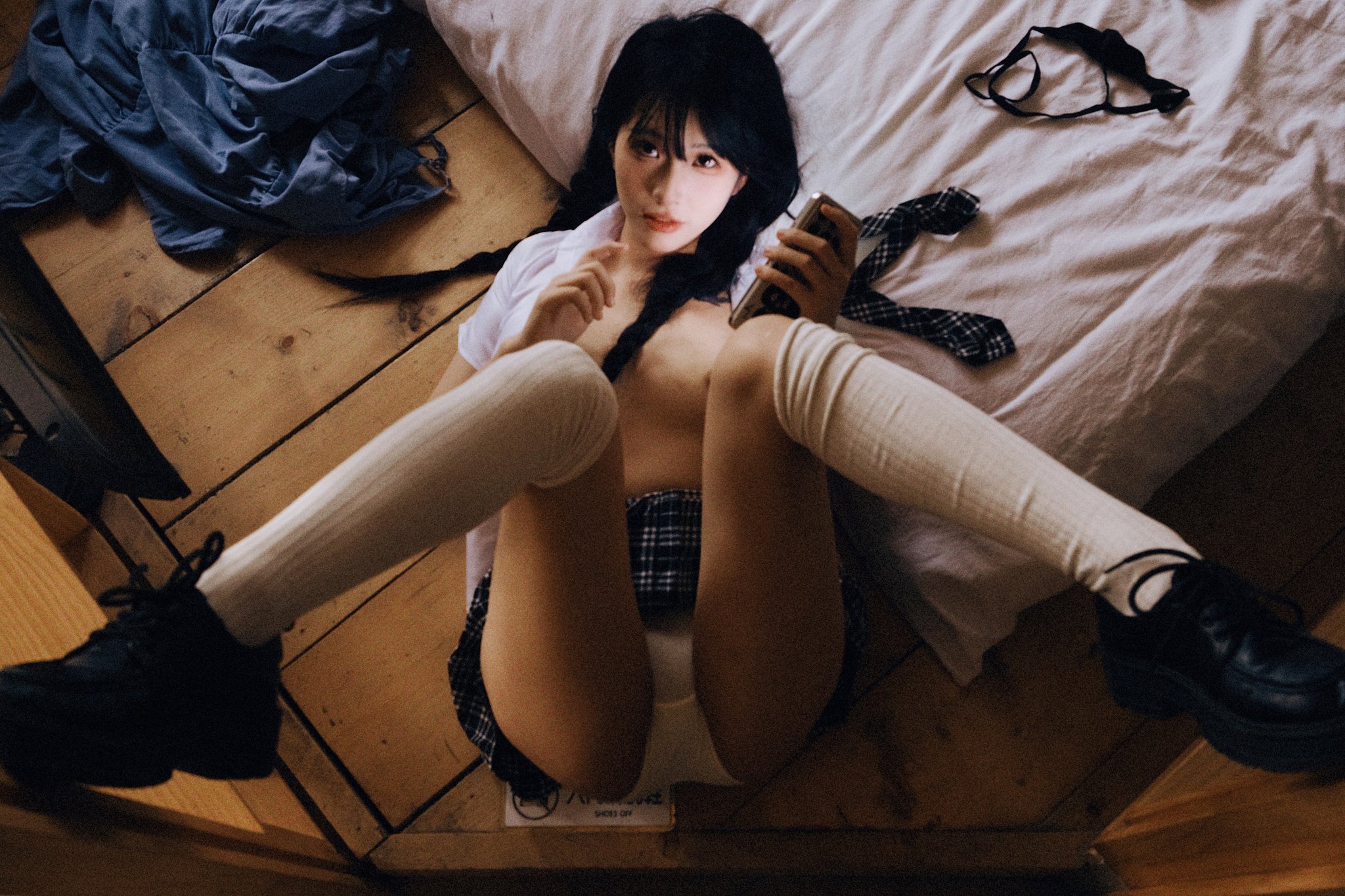 一位穿着白衬衫和黑袜子的女孩躺在床上。