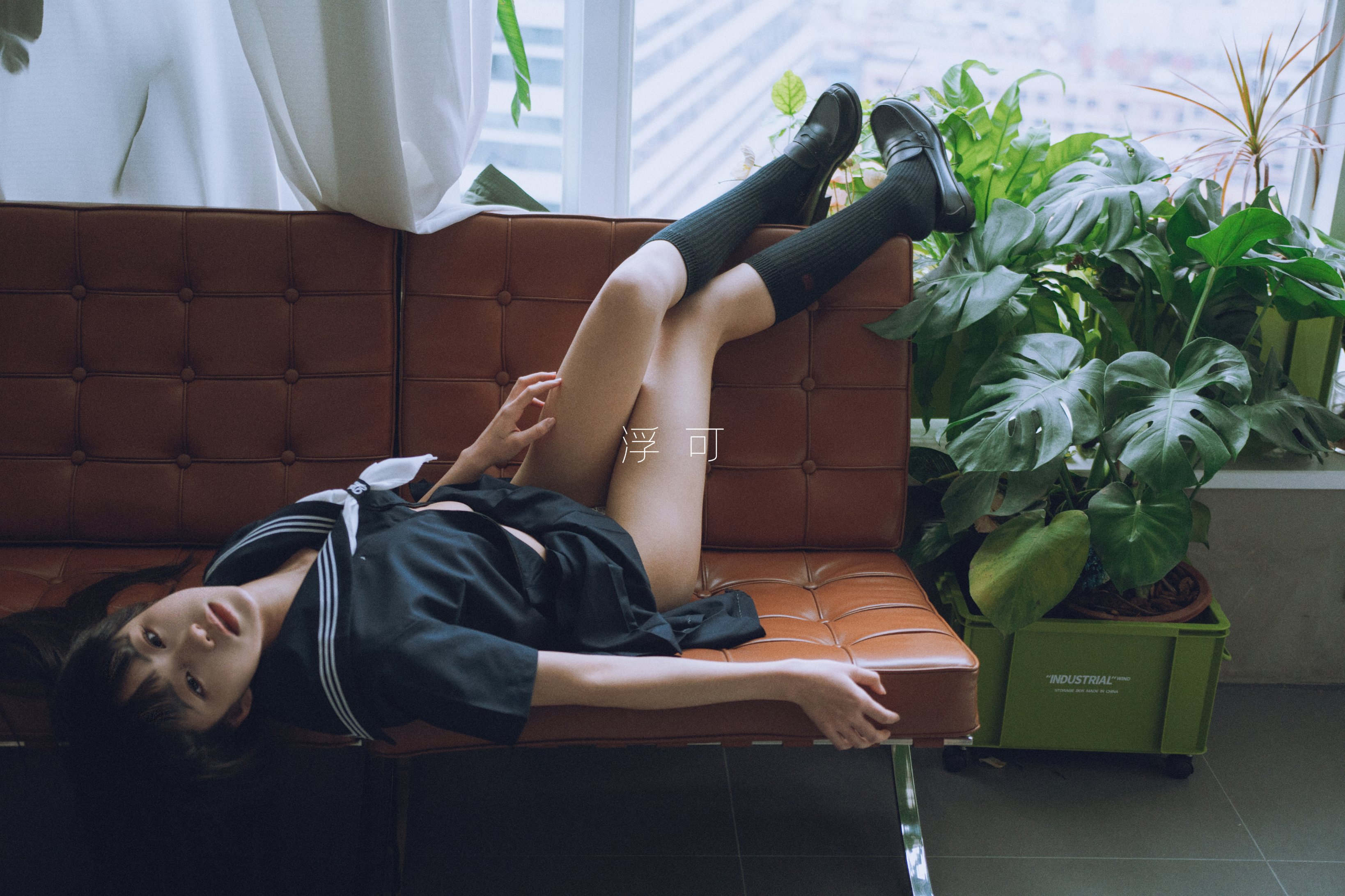 一位穿着黑色衬衫和黑袜子的女人躺在沙发上。