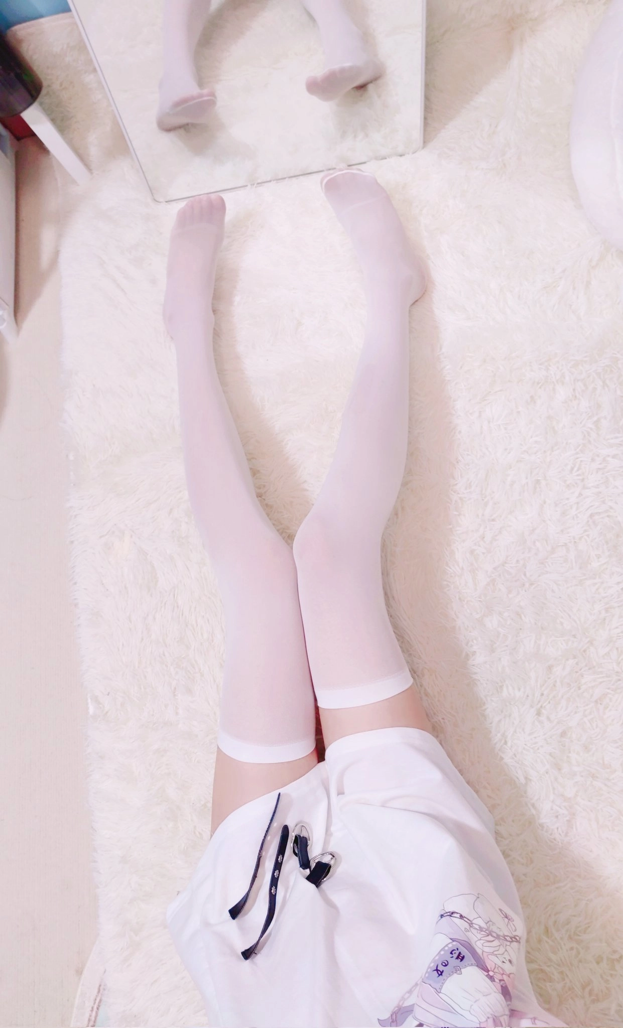 穿着白袜子和一件白色衬衫的人躺在白色地毯上。