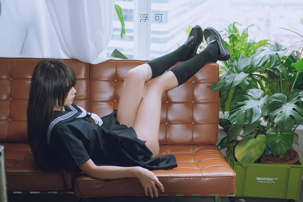 穿着黑色裙子和黑袜子的女人躺在沙发上。