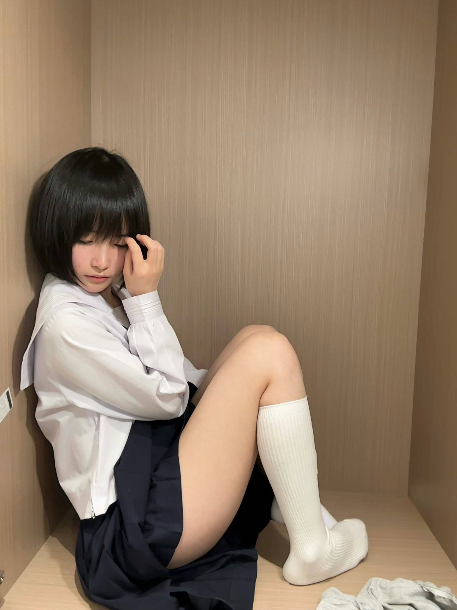 黑发和白衬衫的女孩坐在一个小空间里。