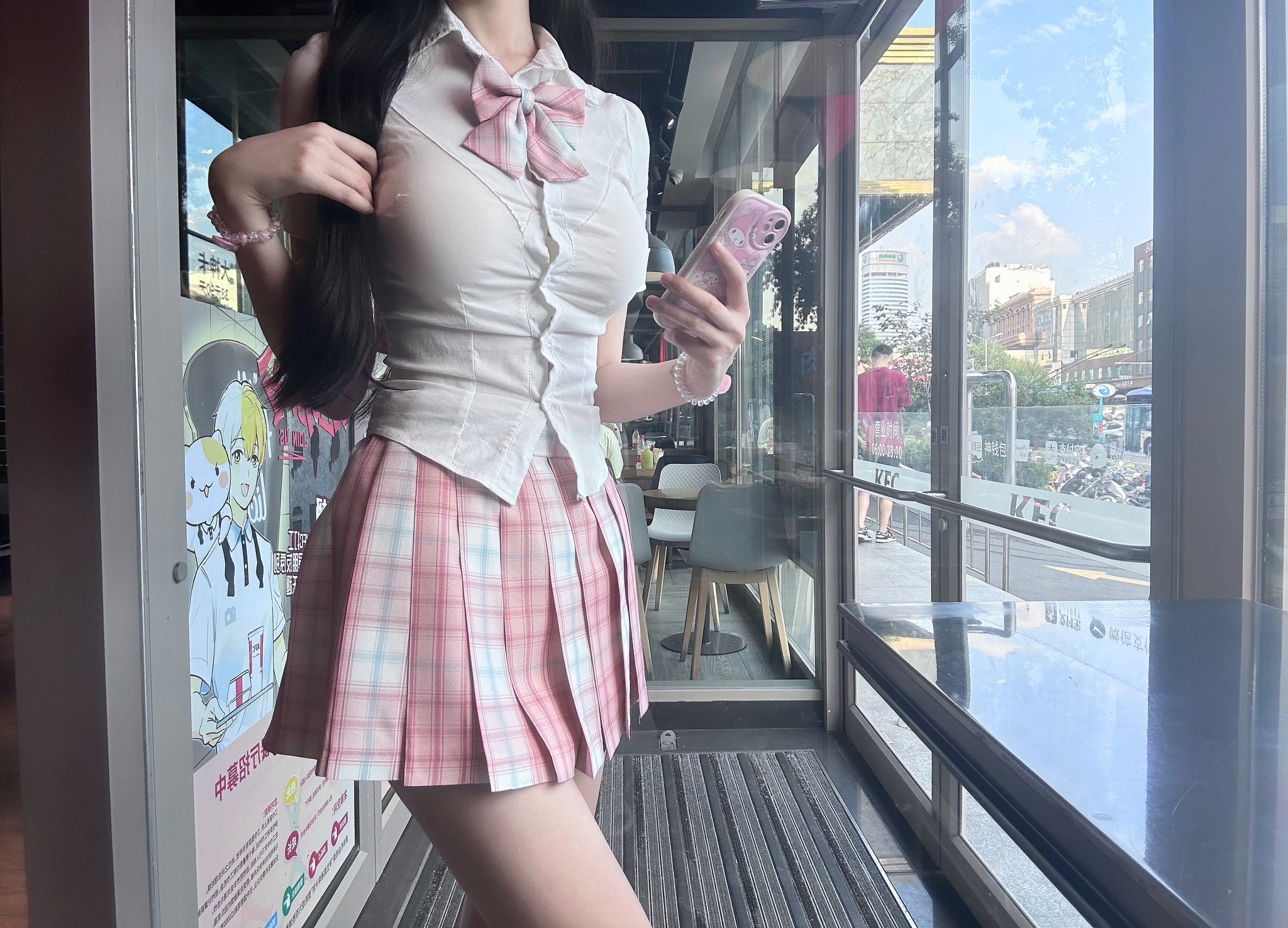 一位穿着白色衬衫和粉红色裙子的女人拿着手机。