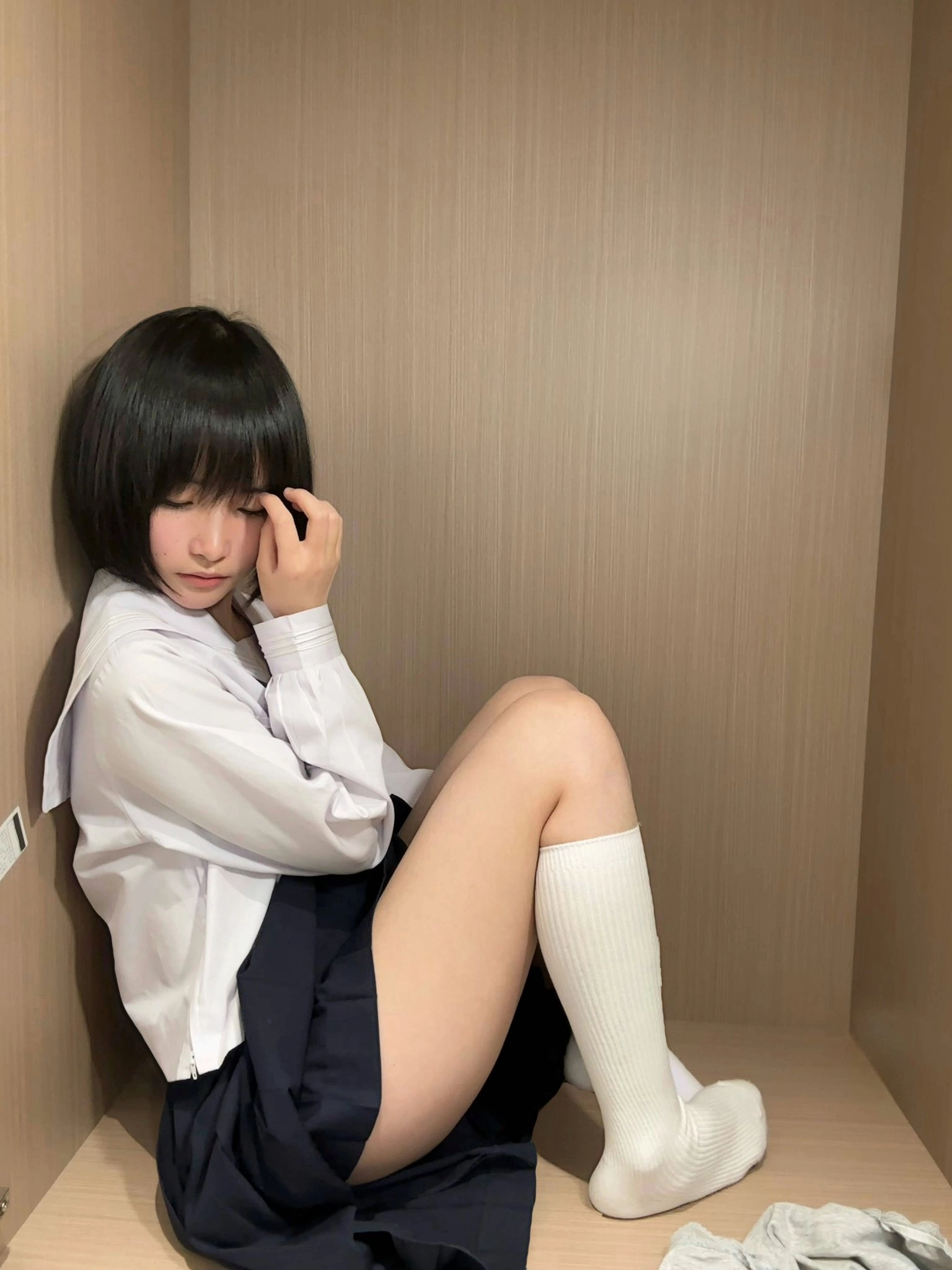 黑发和白衬衫的女孩坐在一个小空间里。