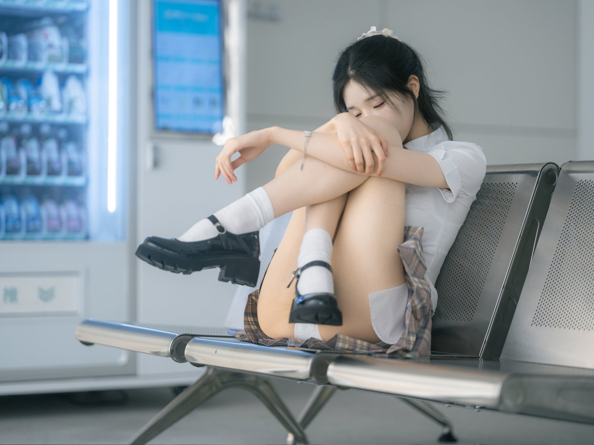 女孩坐在冰箱前面的椅子上。