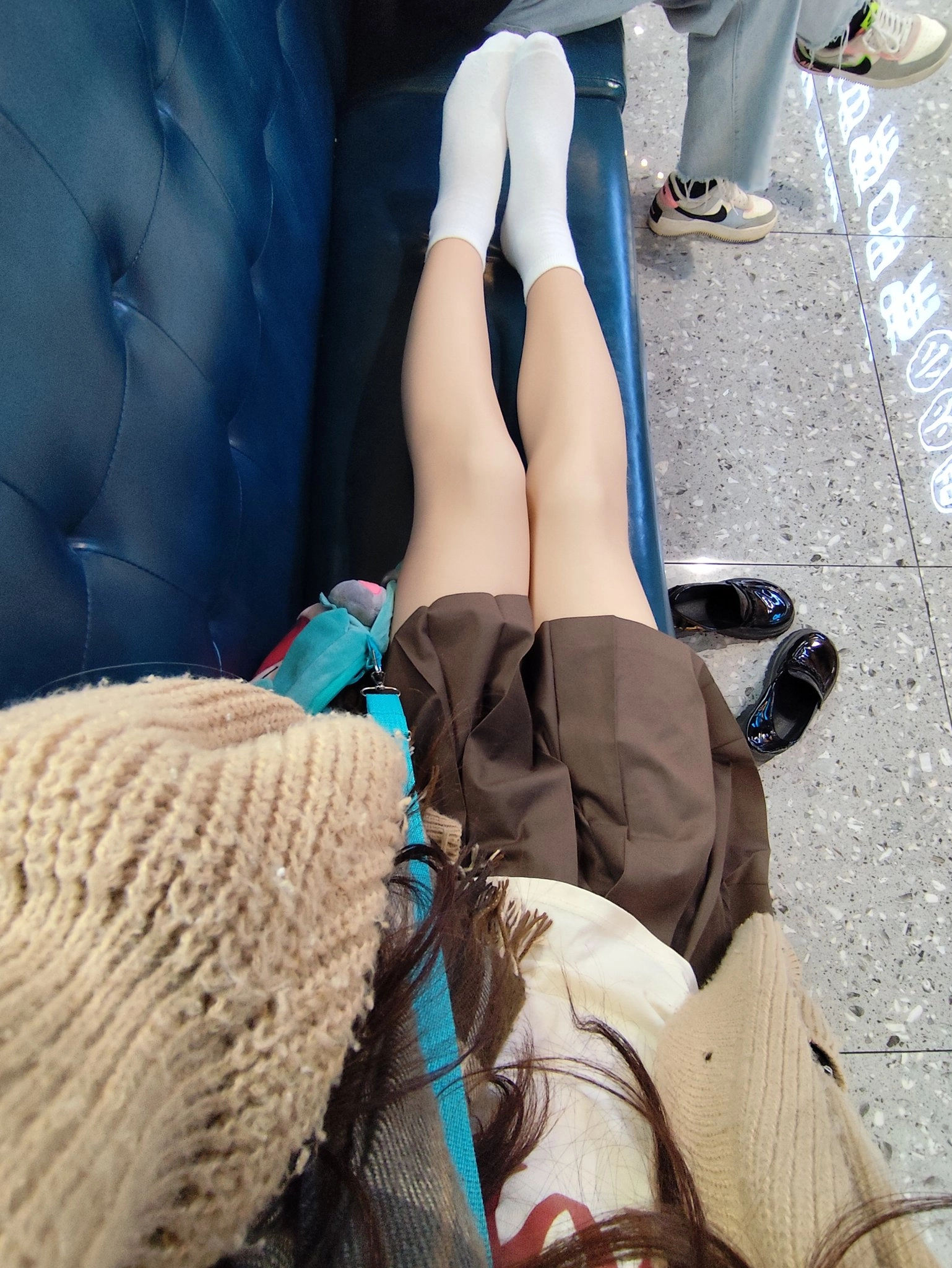 穿着棕色裙子和白色袜子的女人坐在蓝色的沙发上。