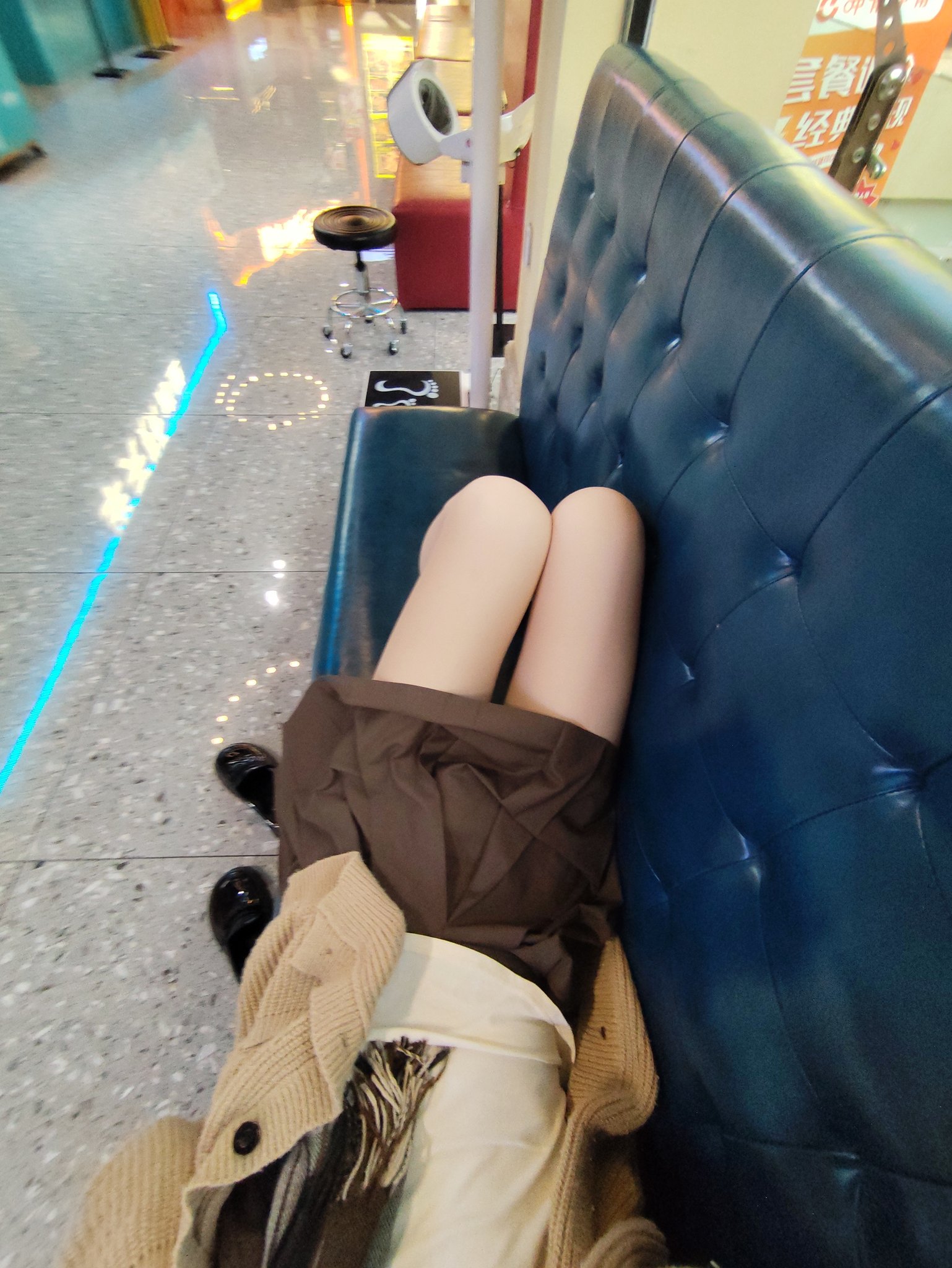 穿着棕色裙子和白色袜子的女人坐在蓝色的沙发上。