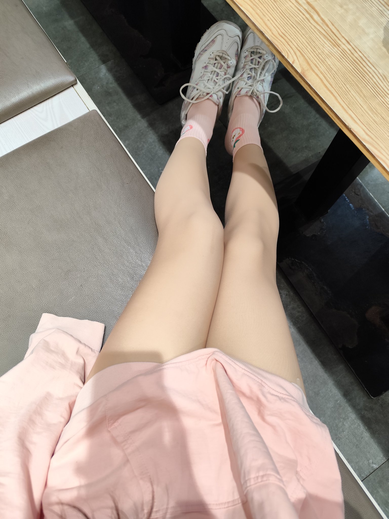 穿着粉红色袜子和粉红色的裙子的女人坐在一个凳子上。