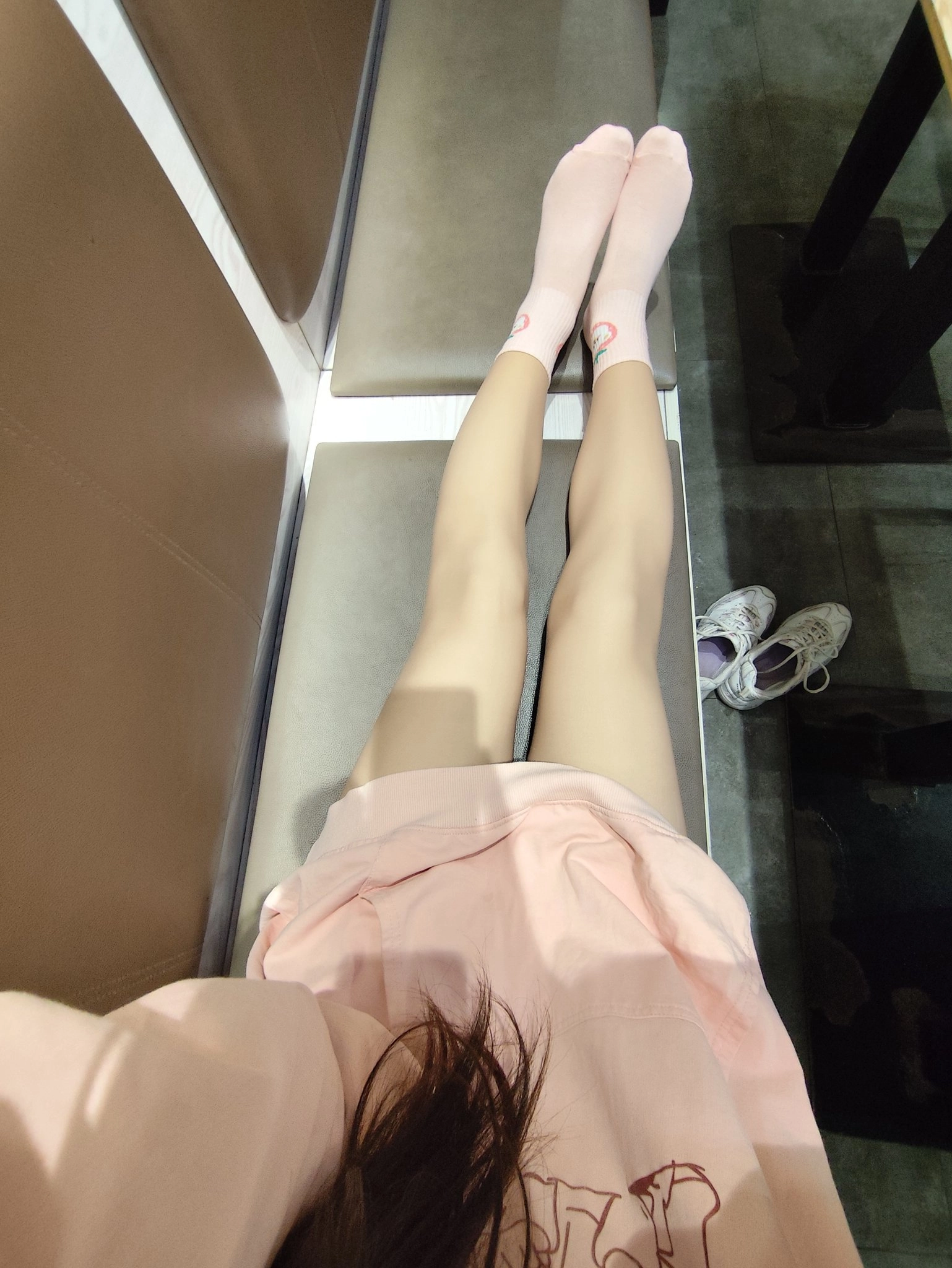 穿着粉红色袜子和粉红色的裙子的女人坐在一个凳子上。