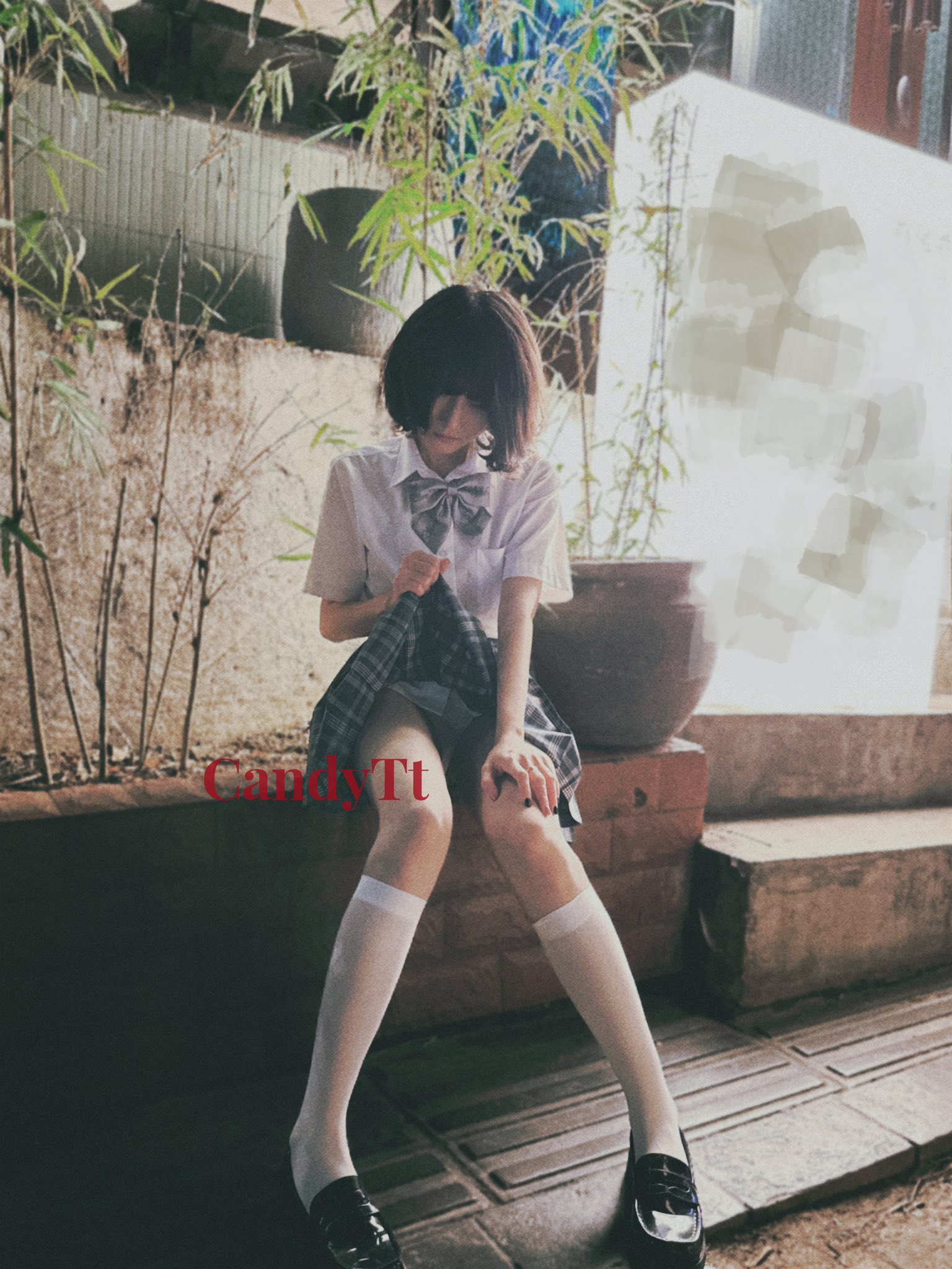 穿着白色衬衫和黑色裙子的女孩坐在砖墙上。