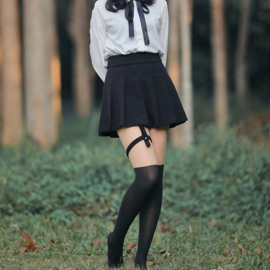 穿着白色衬衫和黑色裙子的女人站在一个田野。