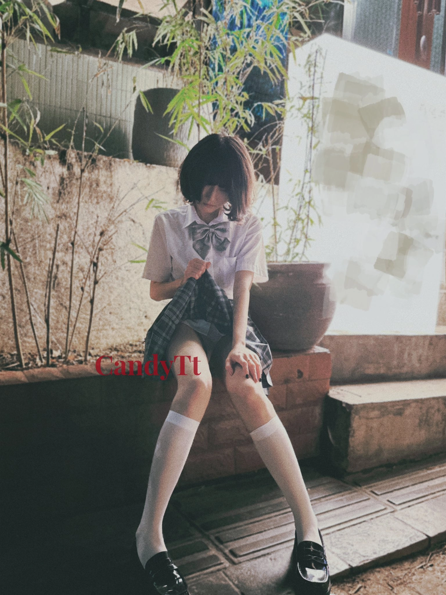 穿着白色衬衫和黑色裙子的女孩坐在砖墙上。