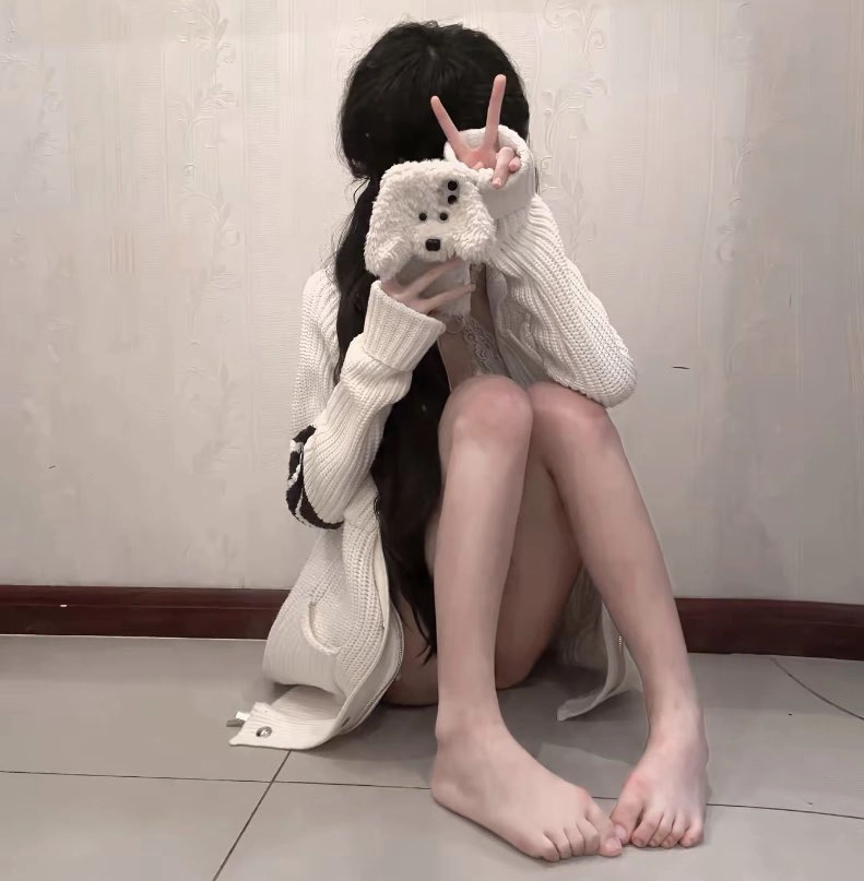 女人坐在地板上,拿着电话。