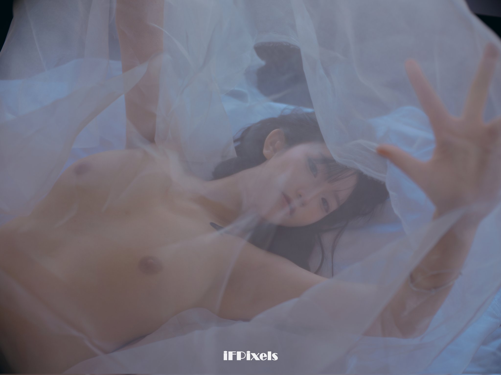 黑头发和纹身的女人坐在床上。