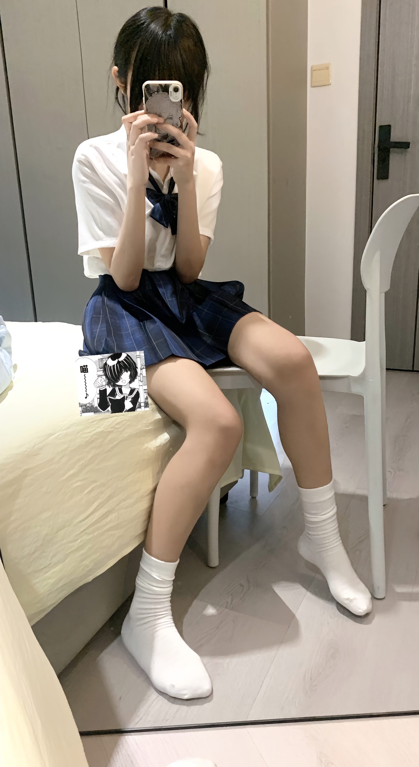 穿着白色衬衫和蓝色裙子的女人坐在椅子上。