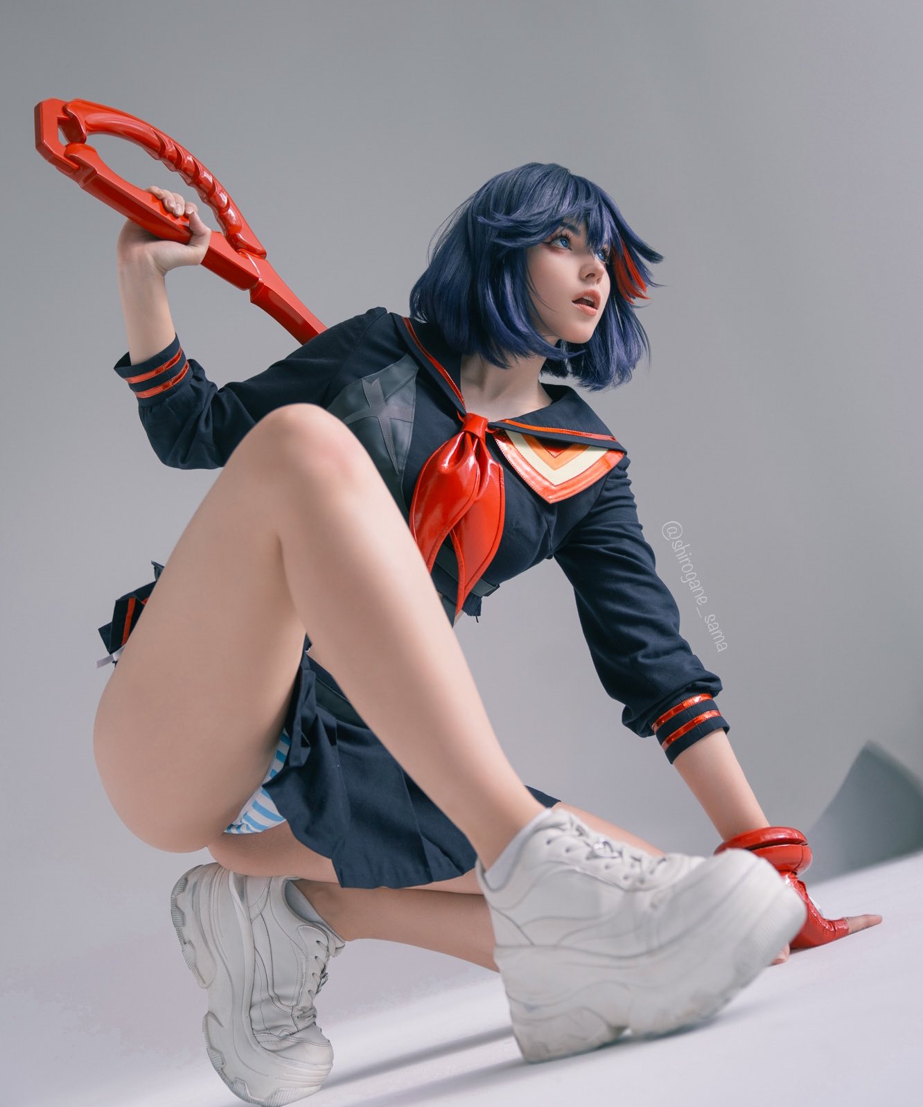 穿着水手服的女人拿着一件红色的物体。