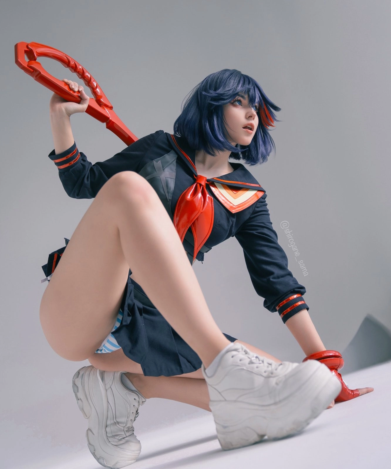 穿着水手服的女人拿着一件红色的物体。