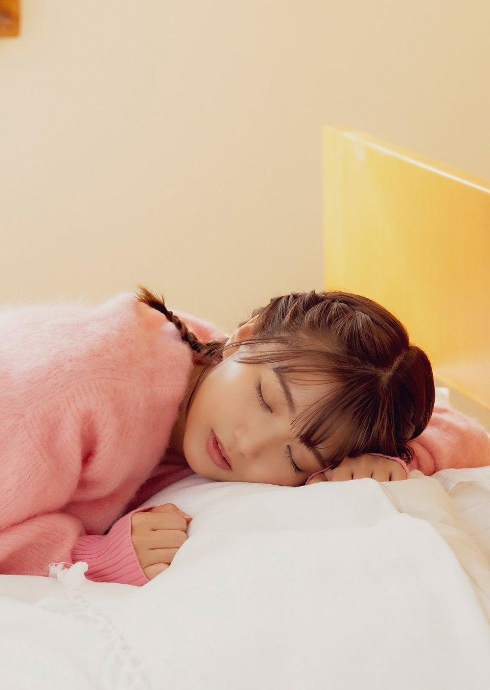 一位穿着粉红色衬衫和内衣的女人躺在床上。