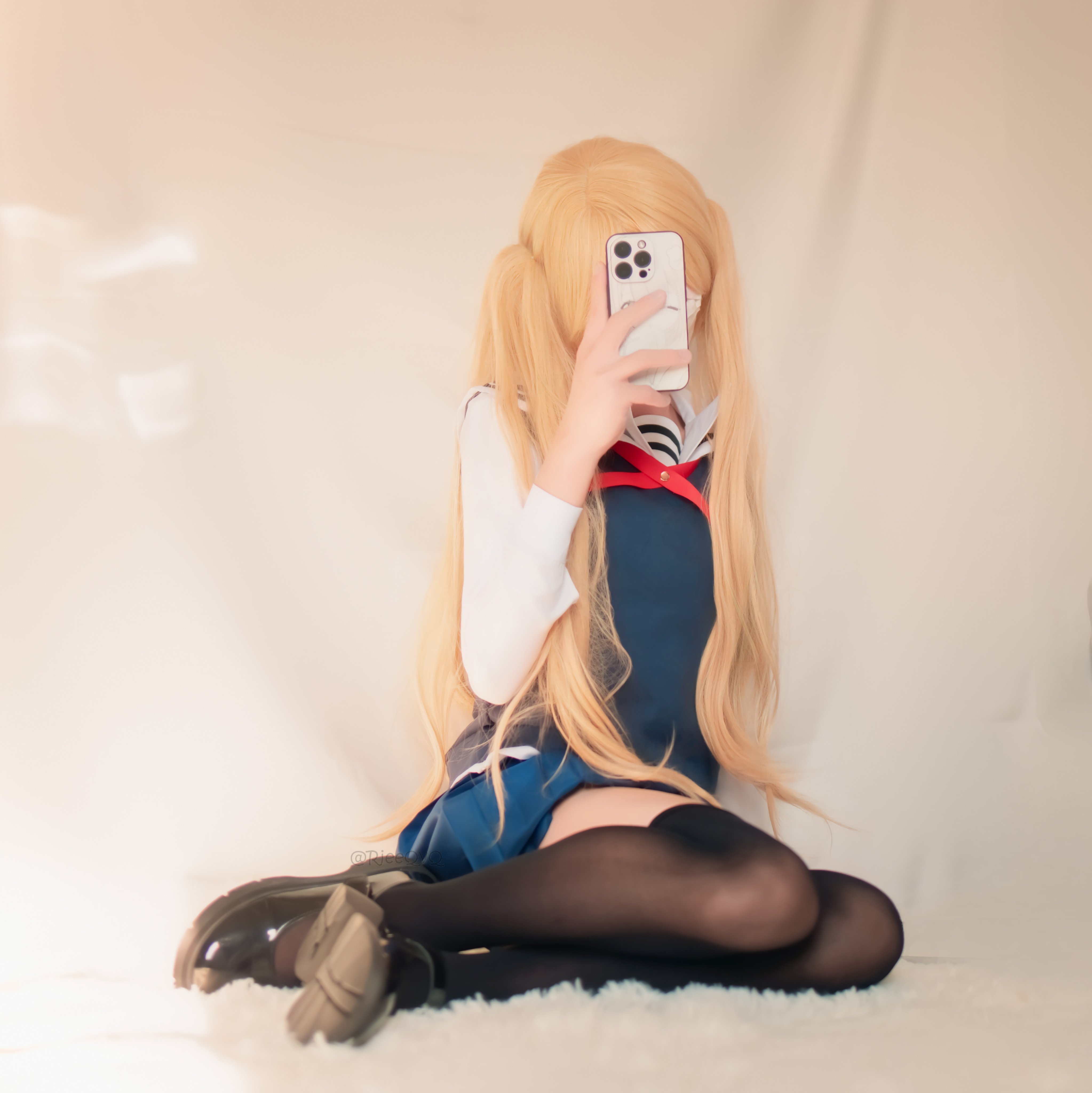 长头发和蓝色和白色水手服的女人拿着手机。