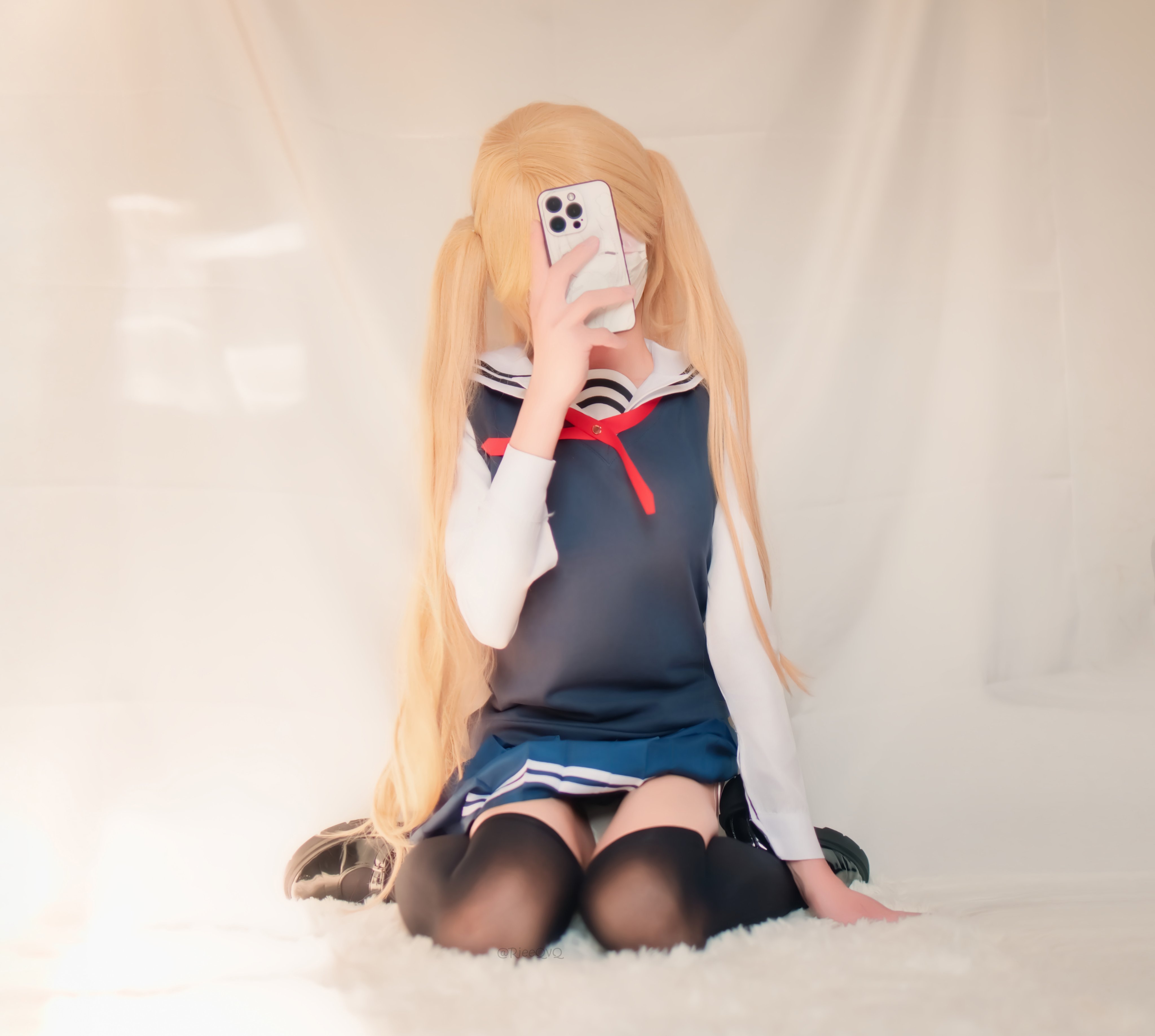 长头发和蓝色和白色水手服的女人拿着手机。