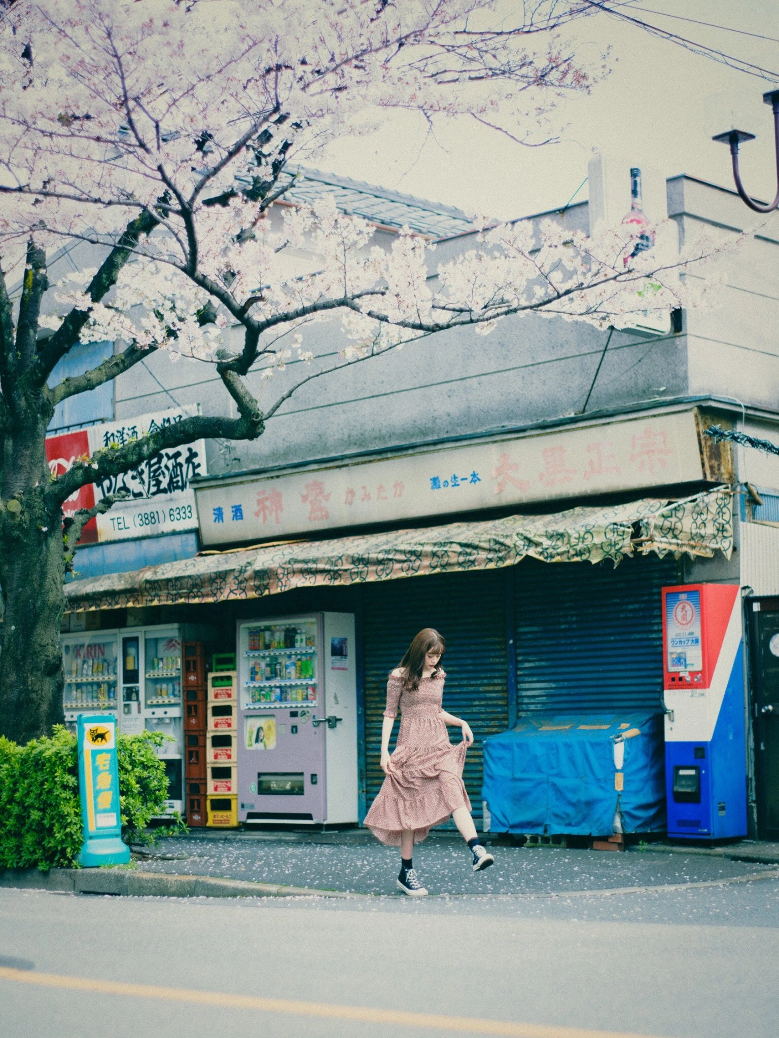 女人走过一个商店,前面有一棵树。