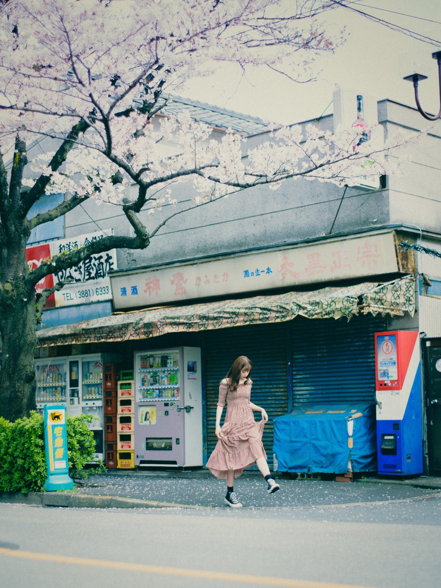 女人走过一个商店,前面有一棵树。