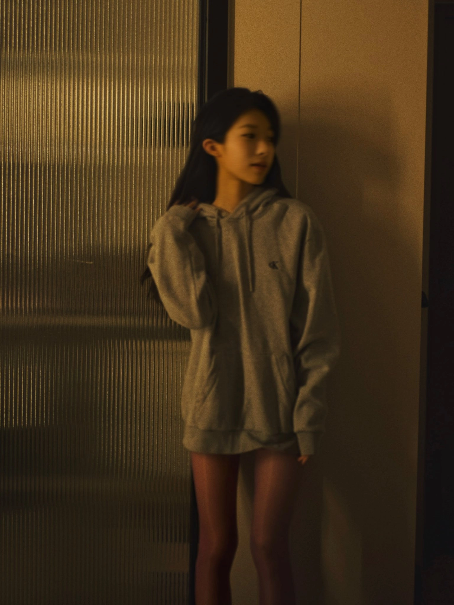 女人穿着灰色的胡迪和粉红色的袜子。