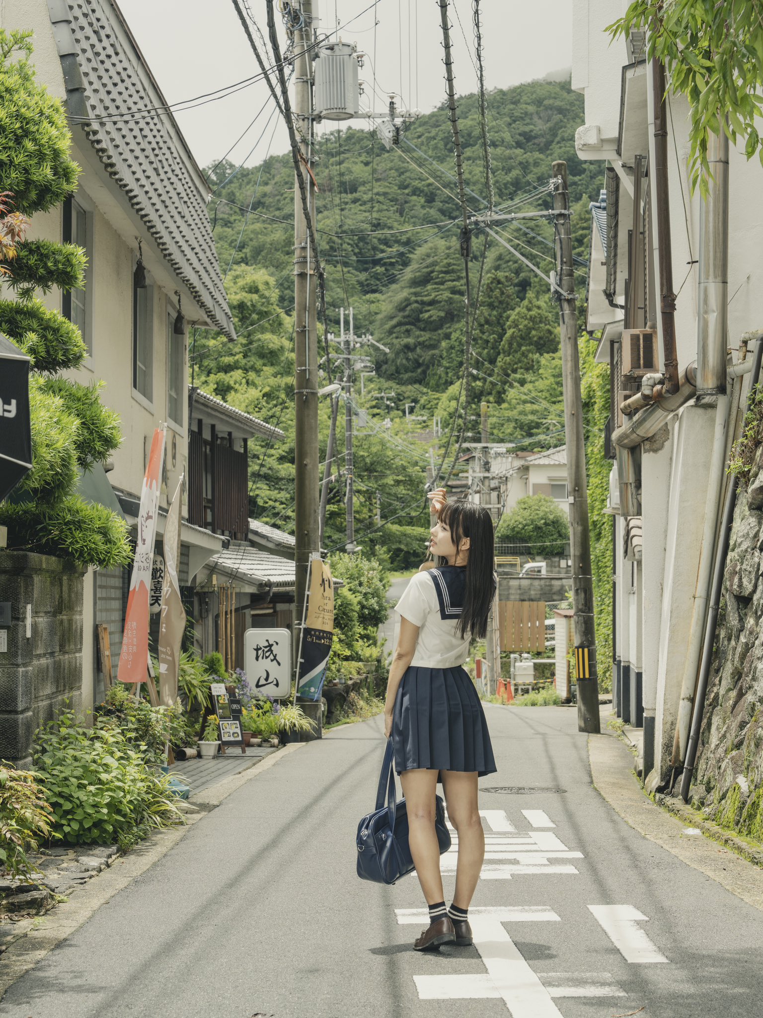 一位穿着蓝色裙子和白色衬衫的女人站在街角。