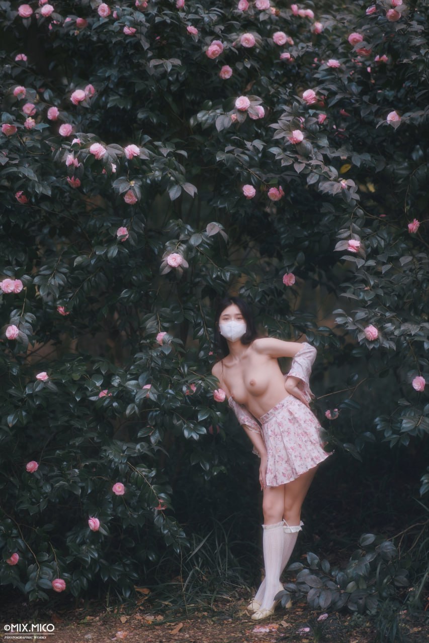 戴着面具的女人站在一棵树前。