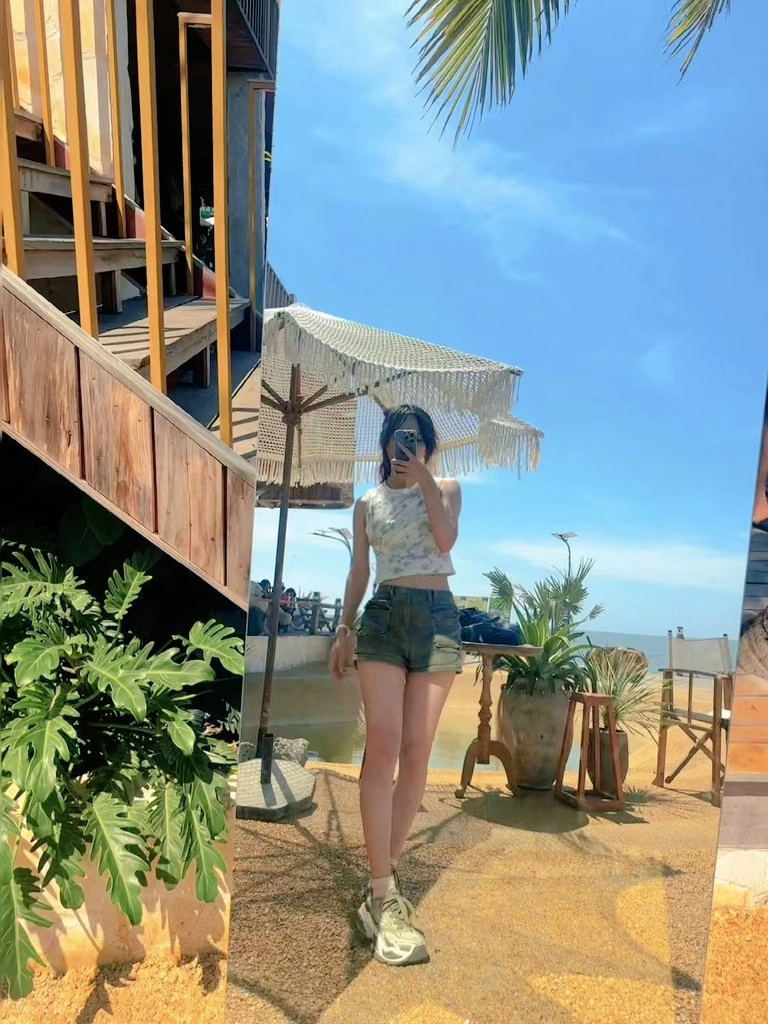 女人在沙滩伞前拍照自己。